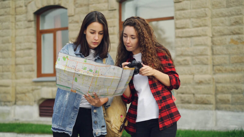 Two female students with a map, exploring a new destination on their journey