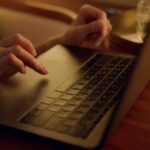 A Person Typing on A Laptop, Likely Googling Your Next Vacation