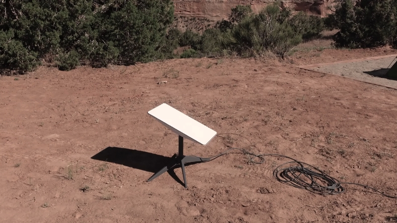 A Starlink Roam dish set up in a dry, remote desert location with a long cable extended for power and connectivity