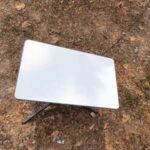 Starlink Roam dish set up on bare ground in a remote area for satellite internet access