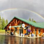 Glacier Park Cabin-style visitor center with green roof and rainbow above