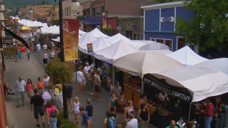 Festival-goers explore food and vendor tents lined up along a busy walkway at Lollapalooza 2025
