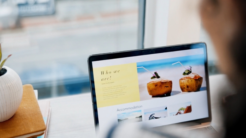 A person checks accommodation options and trip details on a laptop screen as part of pre-trip planning that cuts travel costs