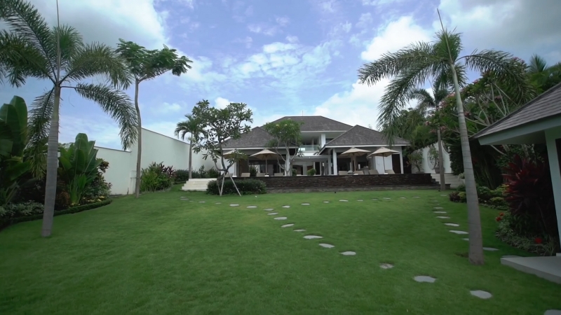 Luxury home in Thailand with palm trees and a large yard, showing where Americans can buy property