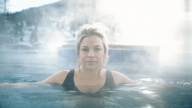 A woman relaxes in a steaming pool at a natural hot springs in Montana during winter