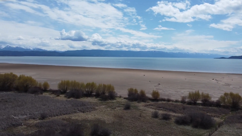 Wide sandy shoreline at Somers Beach State Park with calm water and mountains in the distance