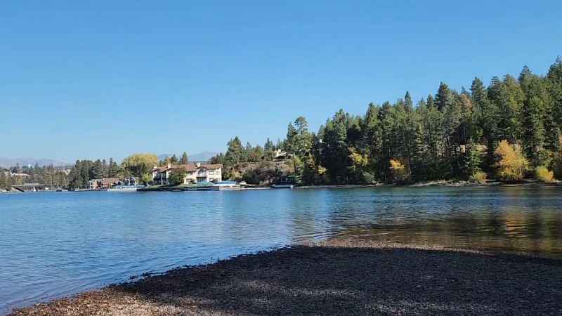 Pebble beach at Wayfarers State Park with clear water and trees along Flathead Lake