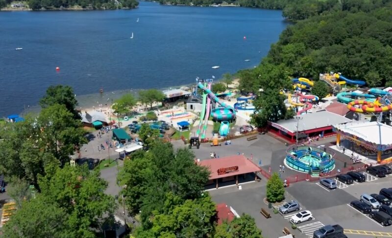 Summer day in Missoula, Montana: a lakeside water park with slides and pools, a beach, and market areas