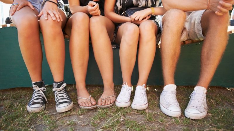 People sitting on a bench at a festival wearing sneakers and sandals