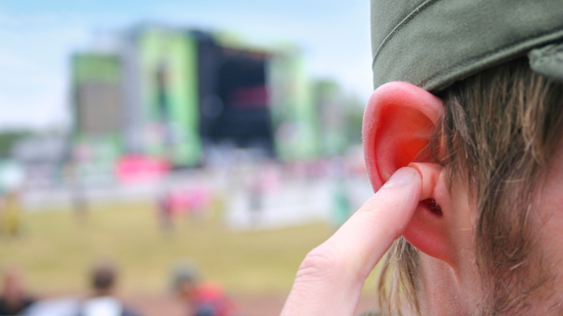 A person placing an earplug in their ear at Bash on the Bay