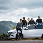 Four friends on a guys trip in Montana with a white car on a mountain road