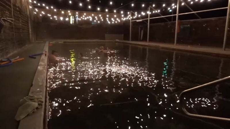 People relax in the warm pool at Jackson Hot Springs Lodge in Jackson, Montana, under string lights at night