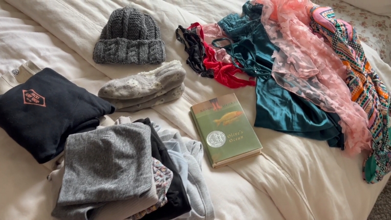 Clothing, sleepwear, swimwear, and a book laid out on a bed for a Montana romantic getaway