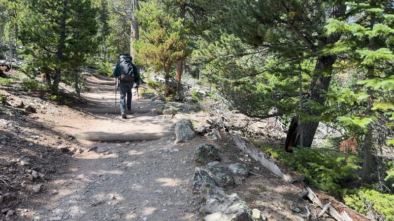 Backpacker on a rocky forest path in Montana on one of the state’s hidden hiking trails