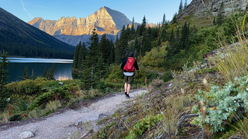 Hiker on the Grinnell Glacier Trail in Montana with mountains and lake in the background