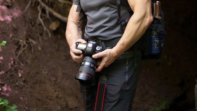 A hiker holds a professional camera on the trail
