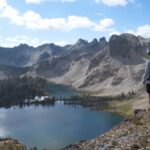 A hiker overlooks alpine lakes and rugged granite peaks in Idaho’s Sawtooth Mountains