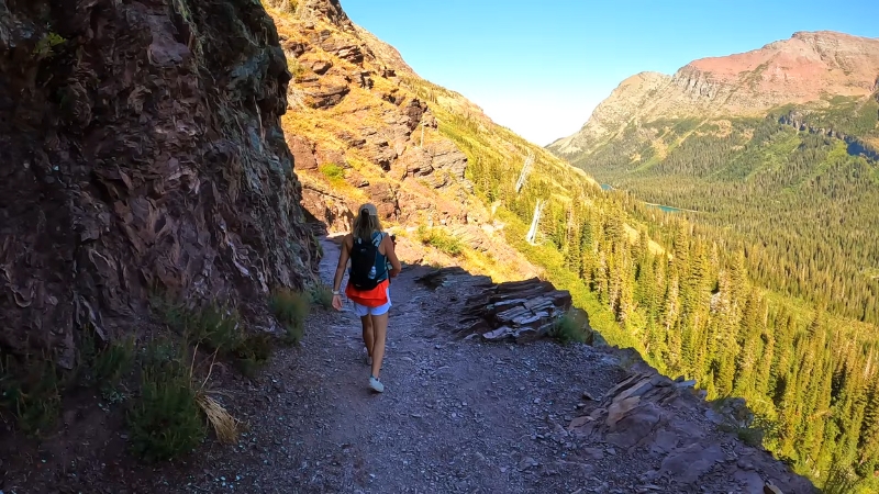 A hiker walks along a rocky trail in Glacier National Park