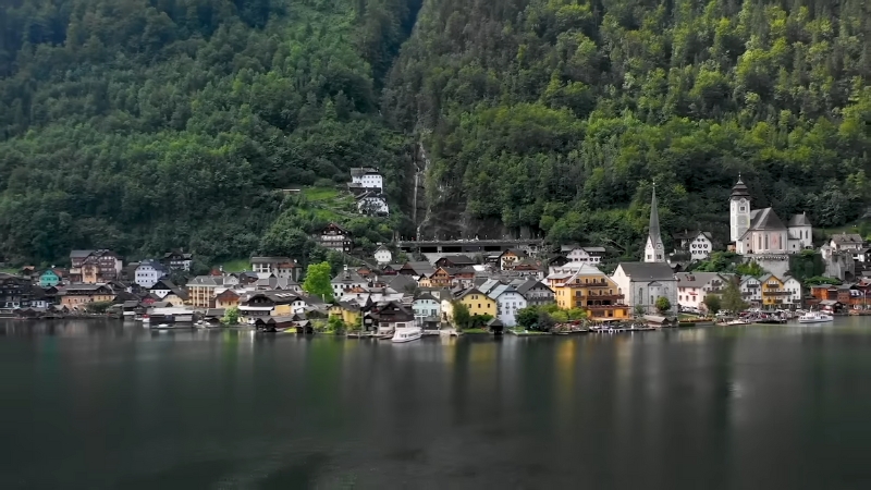 A lakeside Alpine village with traditional houses and churches surrounded by forested mountains