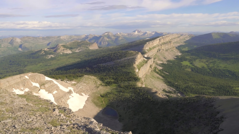 Aerial view of the Bob Marshall Wilderness showing rugged limestone ridges, forested valleys, and patches of lingering snow