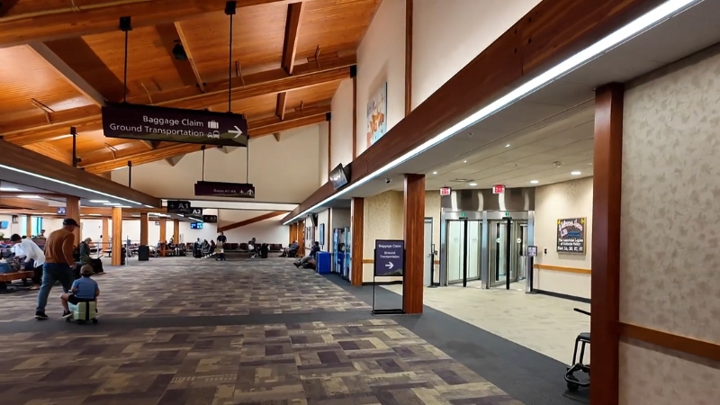 Bozeman Yellowstone International Airport interior shown with passengers seated near the gates under a warm wooden ceiling