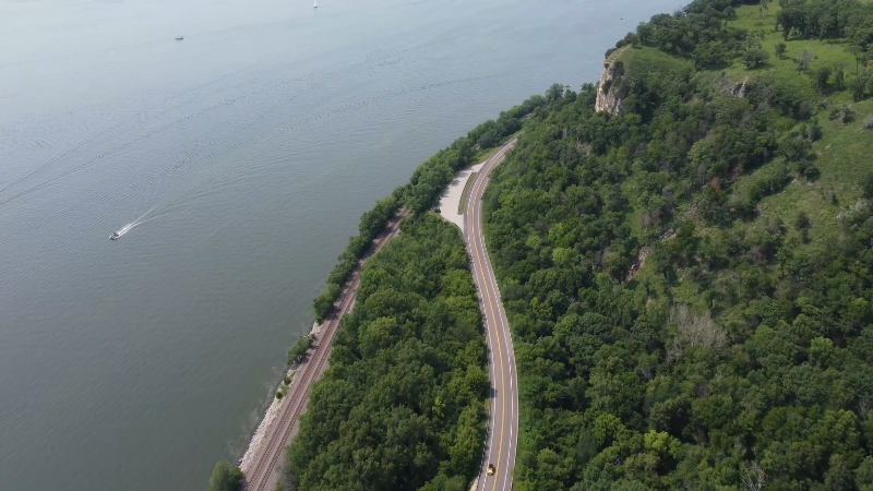 A winding road follows the Mississippi River beside green forests and cliffs