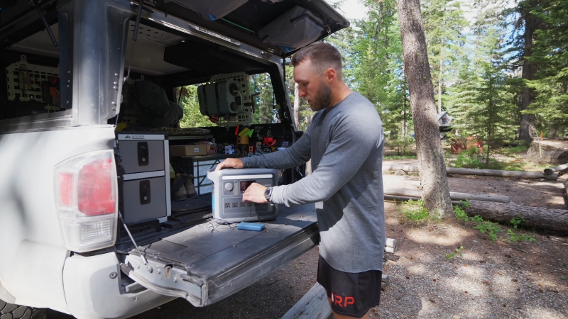 A camper organizes gear at the back of a vehicle while preparing for a trip to Kintla Lake
