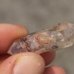 A hand holds a freshly dug quartz crystal from Crystal Park Montana
