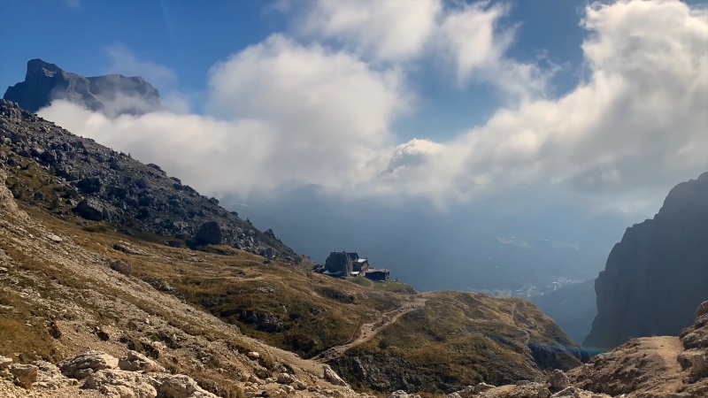 Rocky mountain trail in the Dolomites with a small alpine hut and steep cliffs