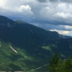 Hiker with a backpack overlooks a wide valley in the Appalachian mountains during a trail hike
