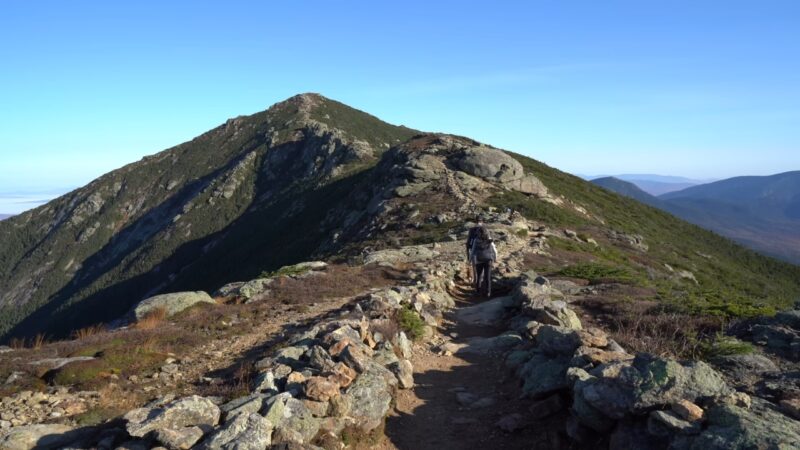 Hiker walks along a rocky ridge trail in the White Mountains of New Hampshire