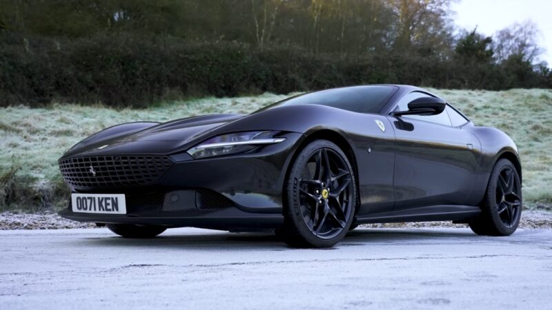 Black Ferrari Roma parked on a road with trees in the background