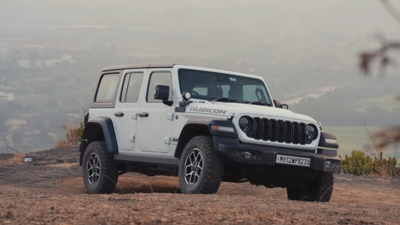 Jeep Wrangler parked on a rugged hillside with a wide landscape view in the background