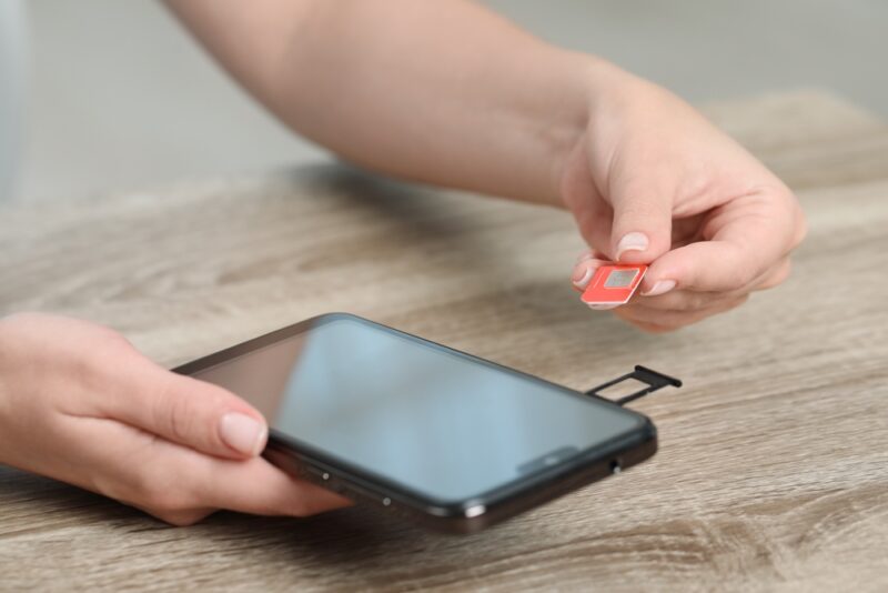 Person inserting a local SIM card into a smartphone for international travel use