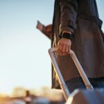 Traveler holding a suitcase and passport while preparing for an international trip