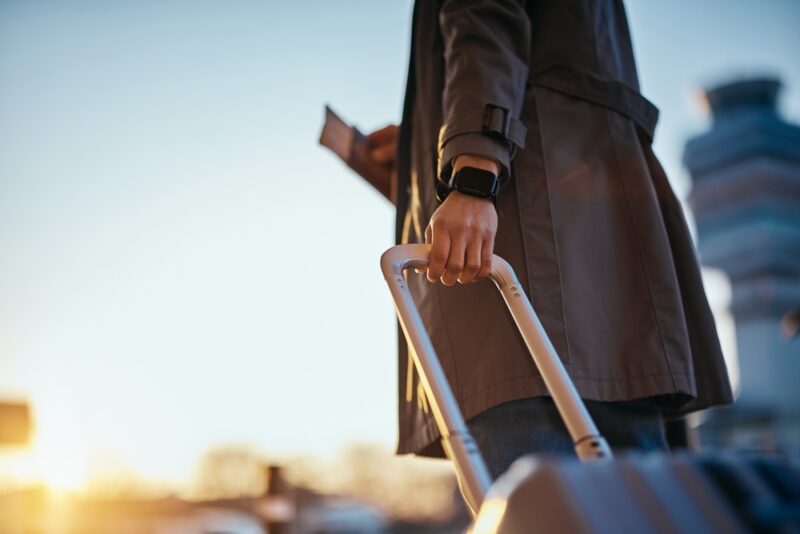 Traveler holding a suitcase and passport while preparing for an international trip